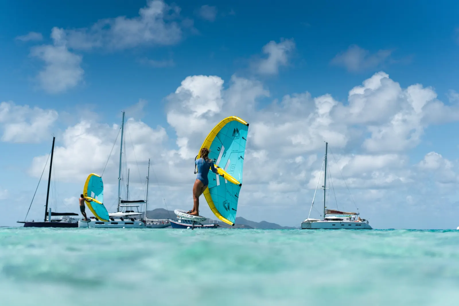 Wing foiling among sailboats and catamarans at anchor